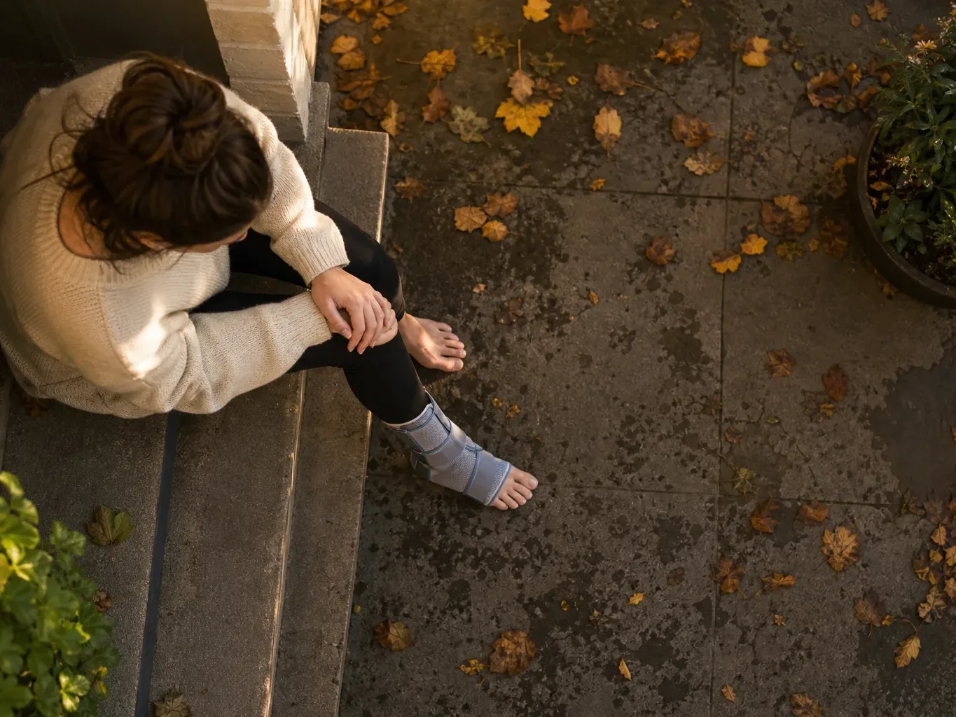 A fall victim with an ankle brace sits on a step near the site of the slip