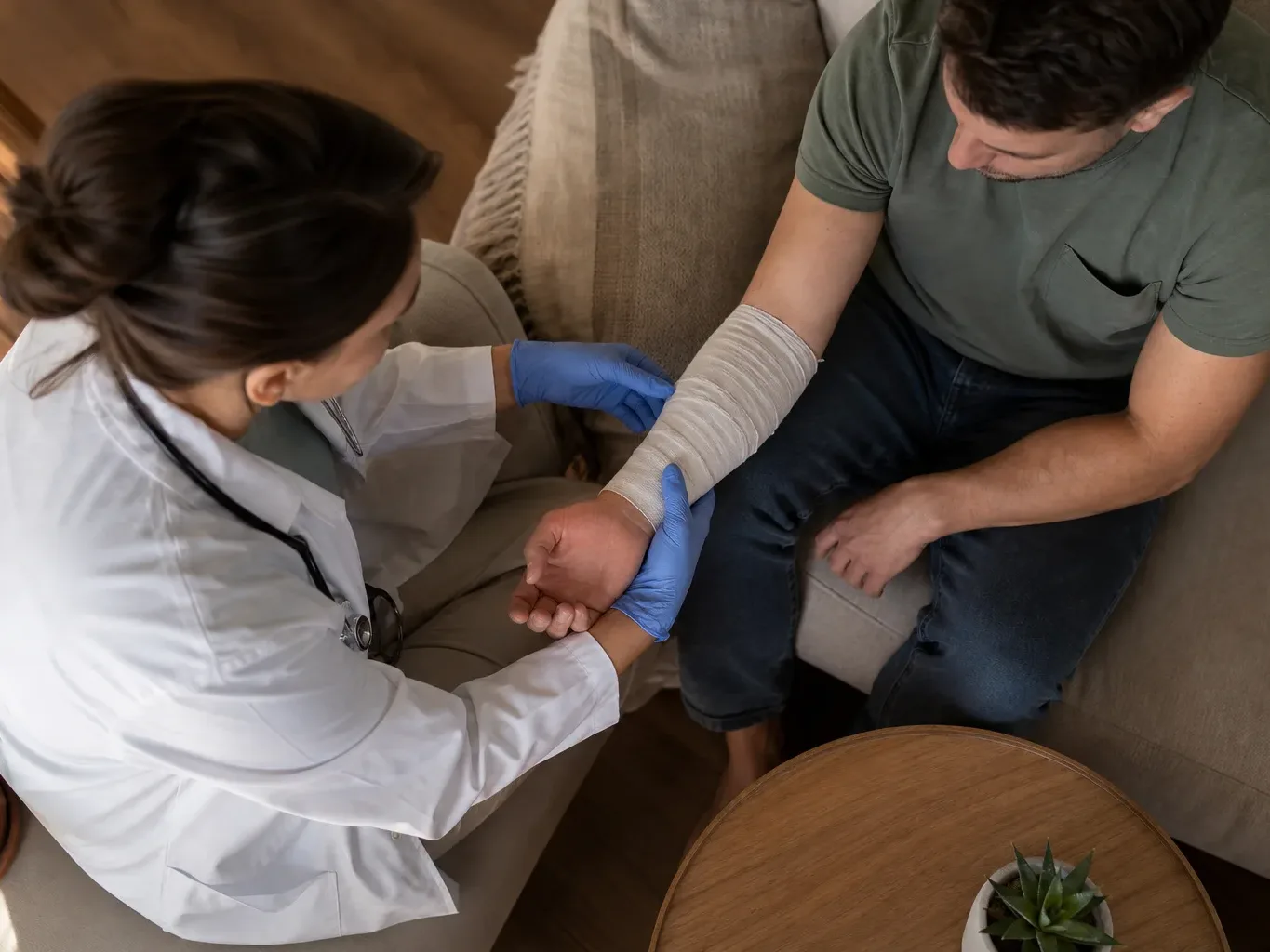 A physician's gloved hands are seen from directly above in cool flat light